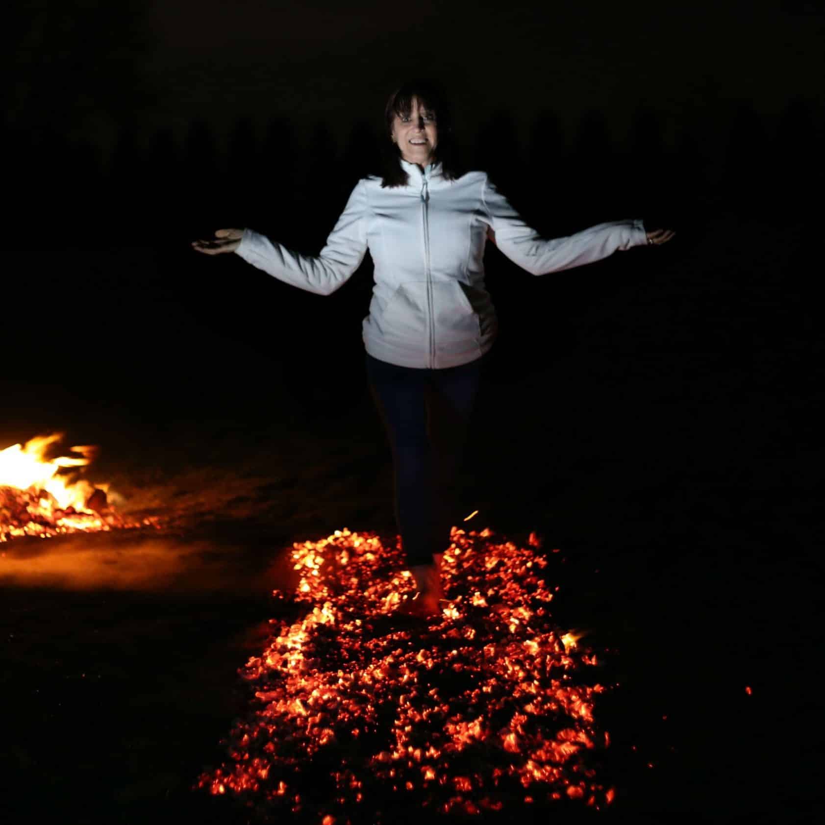 smiling woman walking over bed of glowing red coals